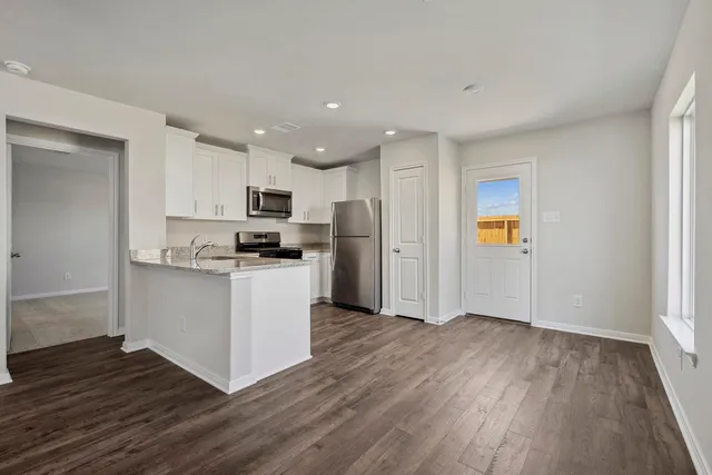 a kitchen with granite countertop wooden floors a stove and a refrigerator