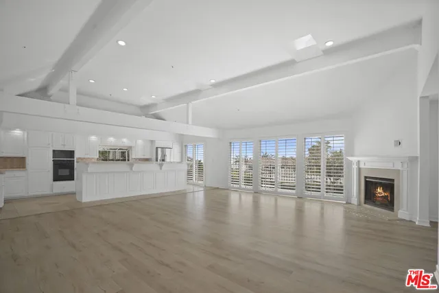 a view of an empty room with wooden floor and a fireplace