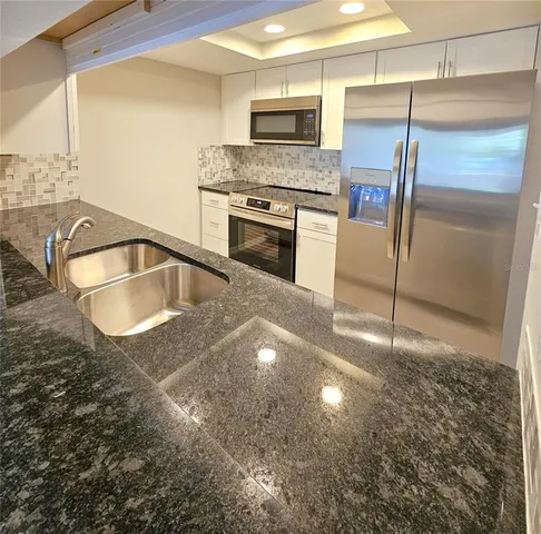 a kitchen with granite countertop a sink stainless steel appliances and a counter top space