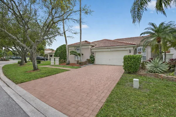 a front view of a house with a yard and palm trees