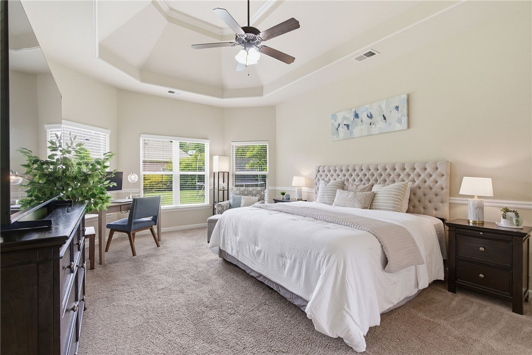 138 Buckland Drive Anderson, SC 29621 - Photo 22 of 49 This spacious primary bedroom features a tray ceiling, ceiling fan, and carpeted floors, creating a comfortable and elegant retreat.