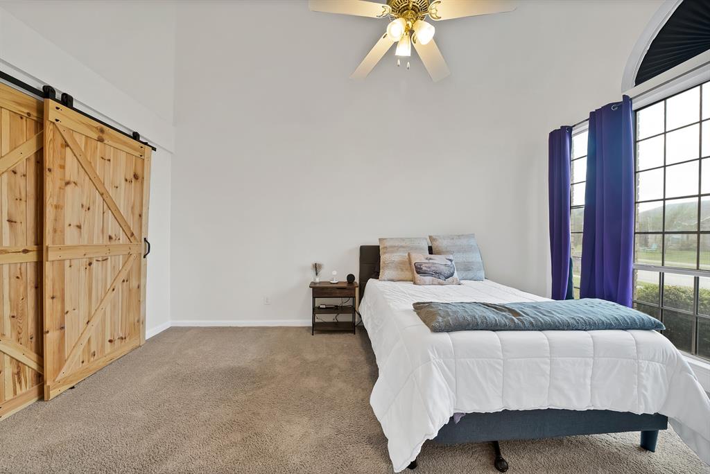 5418 Highgate Lane Rowlett, TX 75088 - Photo 19 of 36 a bedroom with a bed and a chandelier