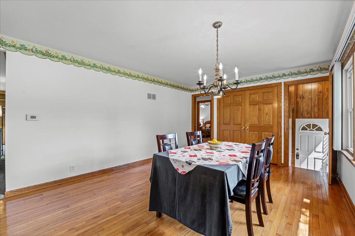 4615 Blue Jay Road Harvard, IL 60033 - Photo 8 of 30 a dining room with wooden floor a chandelier a wooden table and chairs