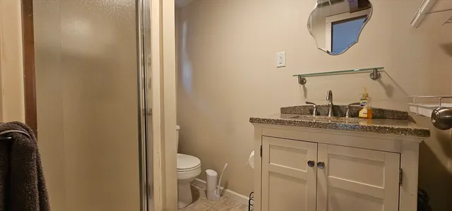a bathroom with a granite countertop toilet sink and mirror