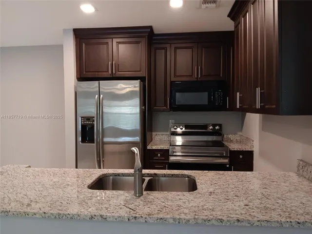 a kitchen with granite countertop a refrigerator and a sink
