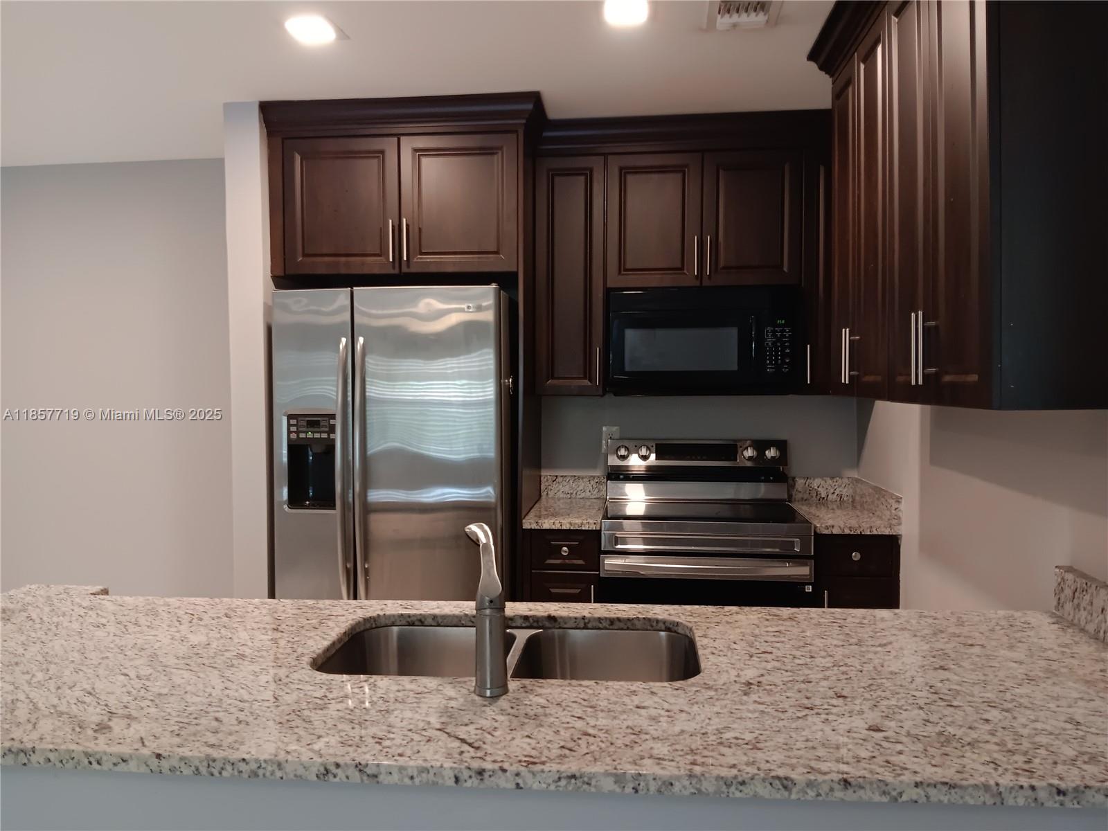 6040 Shaker Wood Circle, Unit 208 Tamarac, FL 33319 - Photo 11 of 25 a kitchen with granite countertop a refrigerator and a sink