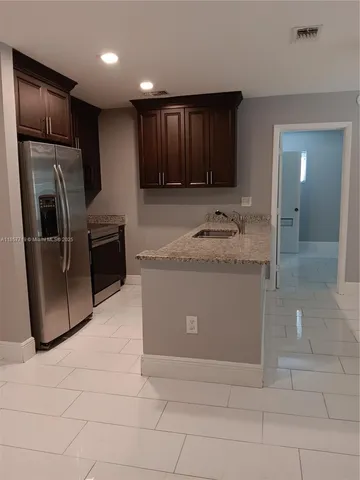 a kitchen with stainless steel appliances granite countertop a refrigerator and a sink