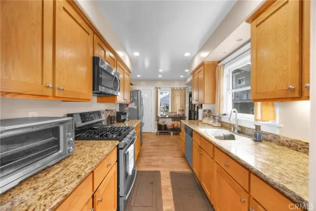 a kitchen with granite countertop a sink a stove and cabinets