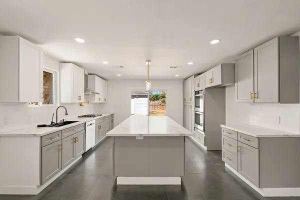a kitchen with stainless steel appliances kitchen island granite countertop a sink stove and refrigerator