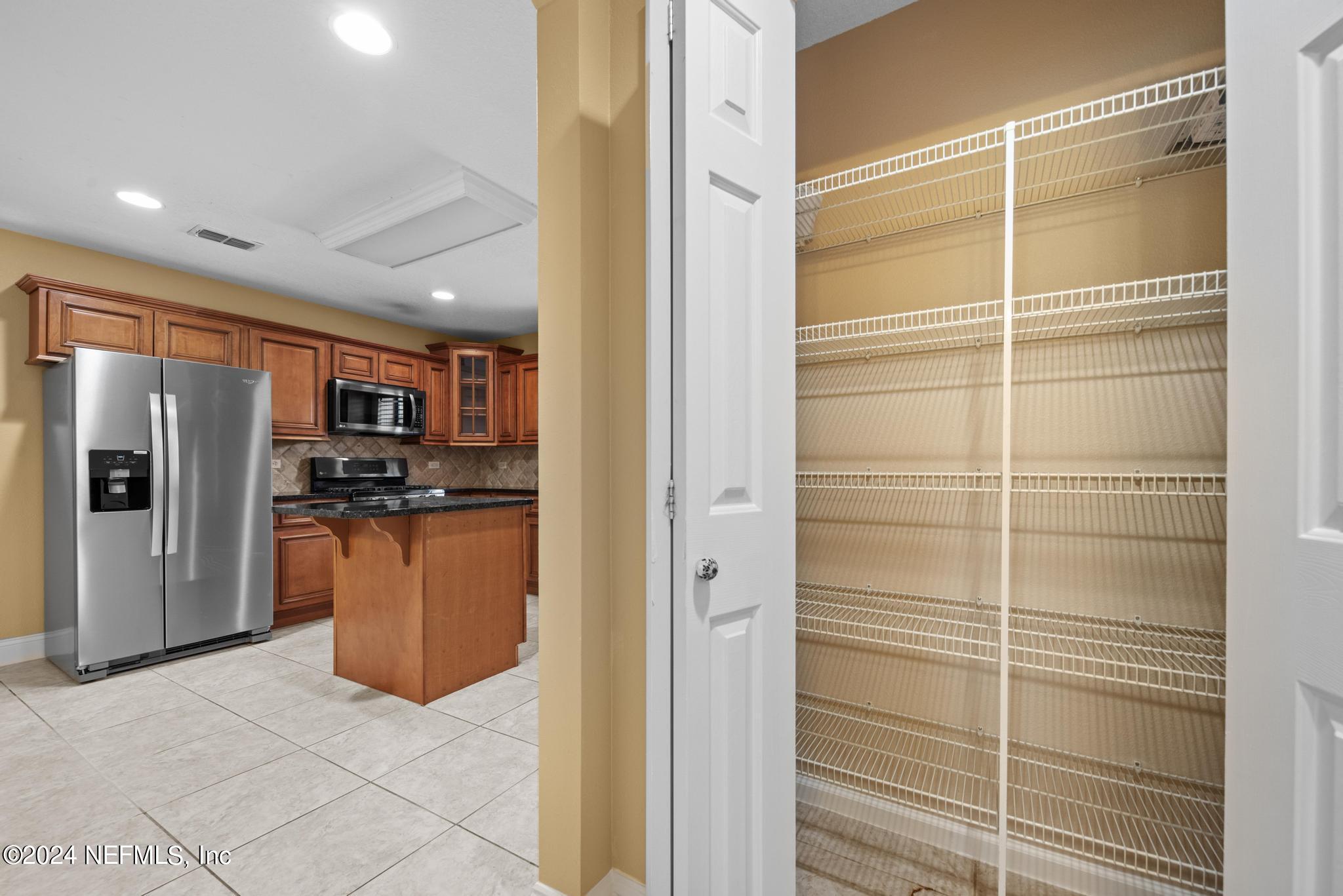 218 Lily Road St. Augustine, FL 32086 - Photo 24 of 28 a kitchen with stainless steel appliances kitchen island granite countertop a refrigerator and cabinets