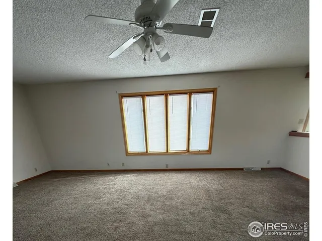 an empty room with a ceiling fan and window