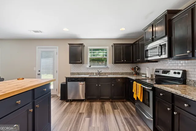 a kitchen with stainless steel appliances granite countertop wooden cabinets a stove top oven a sink and dishwasher