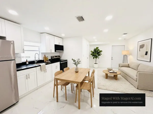 a open kitchen with stainless steel appliances granite countertop a stove top oven a sink a dining table and chairs with wooden floor