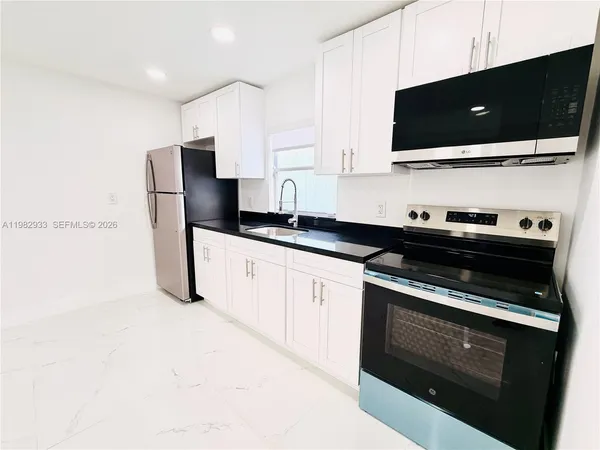 a kitchen with stainless steel appliances a stove a microwave a sink and cabinets