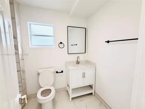 a bathroom with a toilet sink a mirror and vanity