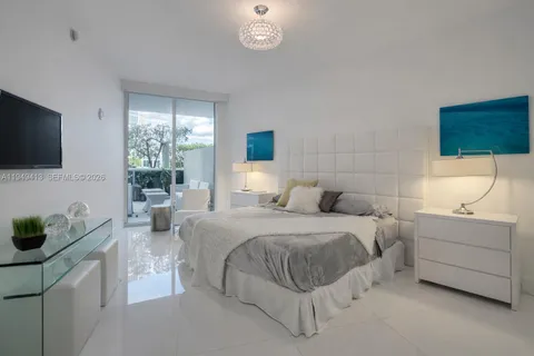 a bedroom with a bed a flat screen tv and a window