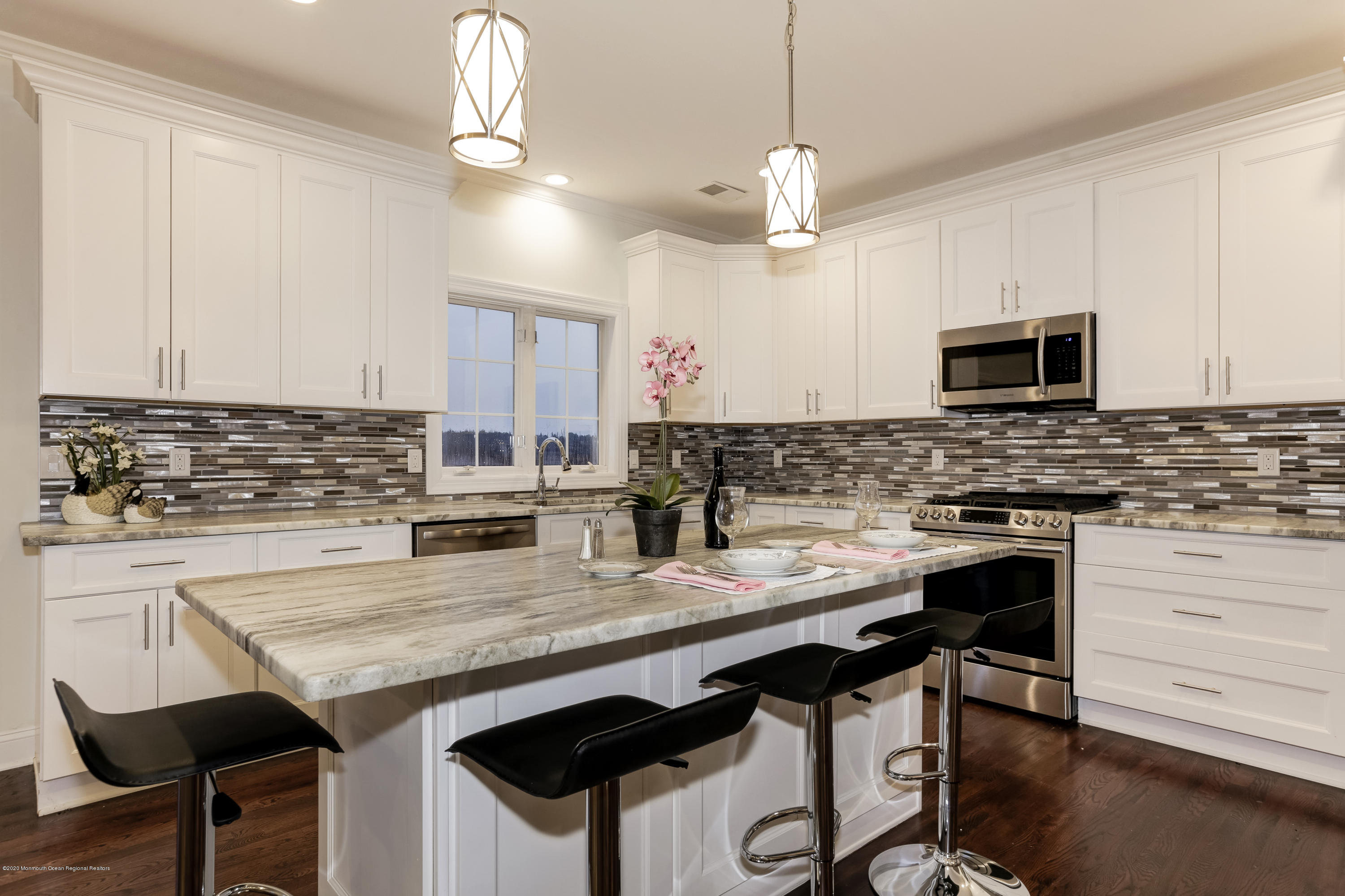 153 Royal Drive Brick, NJ 08723 - Photo 8 of 32 a kitchen with granite countertop a stove a sink a dining table and chairs with wooden floor