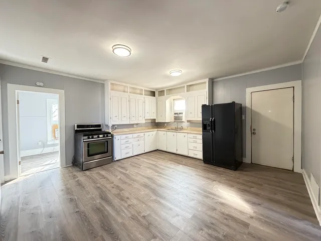 a kitchen with stainless steel appliances wooden floor and white cabinet
