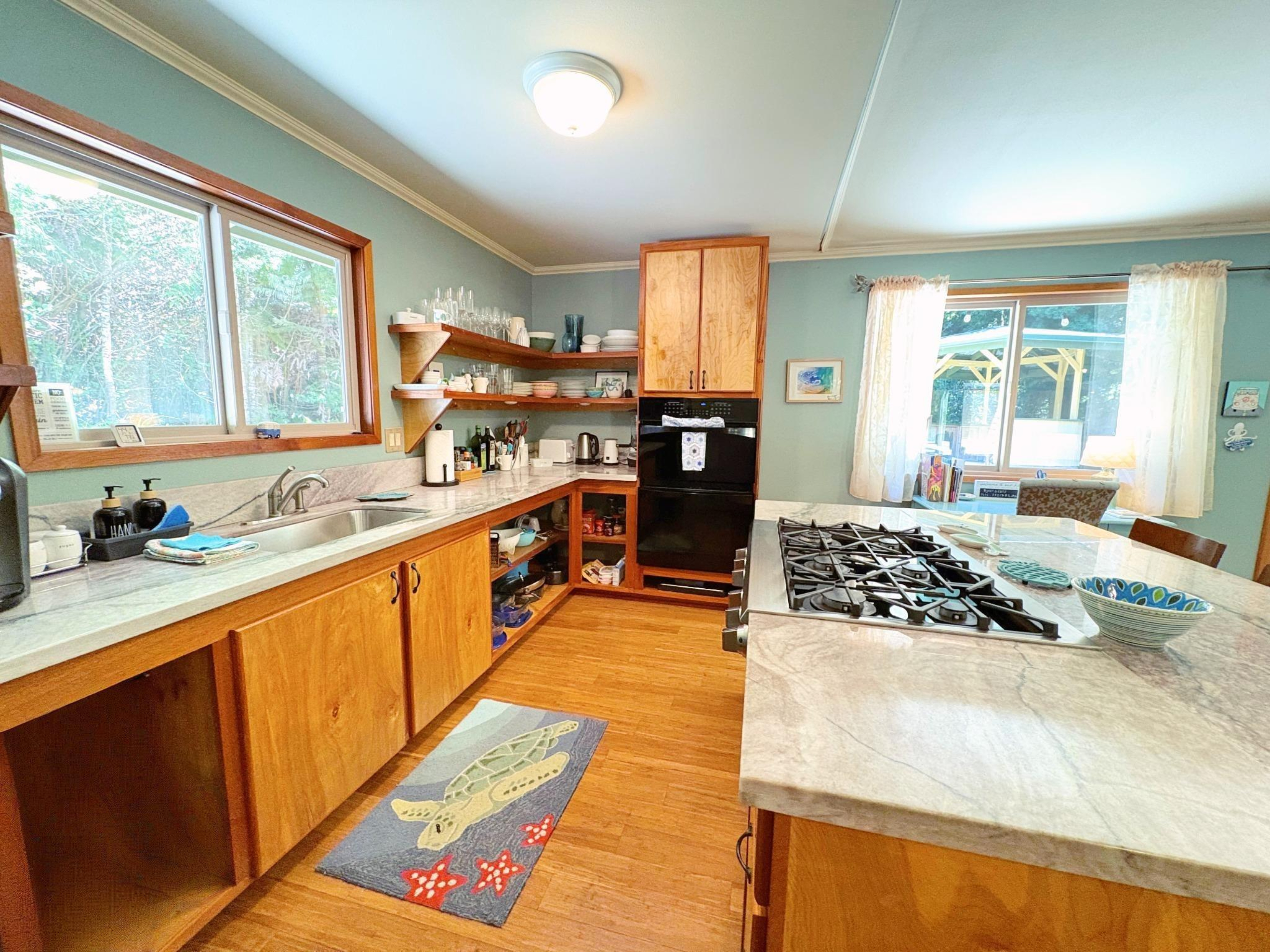 19-4218 Kawailehua Road Volcano, HI 96785 - Photo 6 of 30 a large kitchen with stainless steel appliances granite countertop a stove top oven a sink dishwasher a dining table and chairs with wooden floor