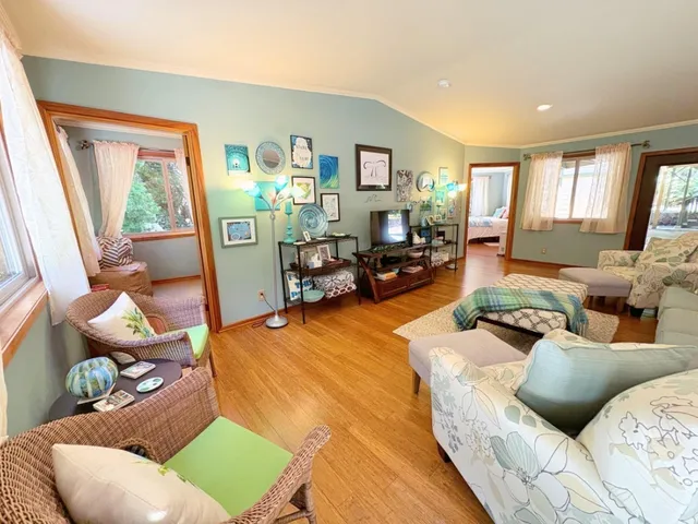 a living room with furniture large window and wooden floor