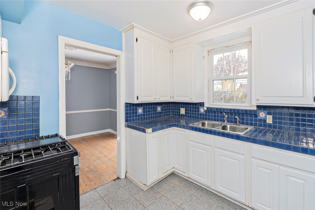 3719 Berkeley Road Cleveland Heights, OH 44118 - Photo 9 of 44 Kitchen with tile counters, black gas range oven, tasteful backsplash, and white cabinetry