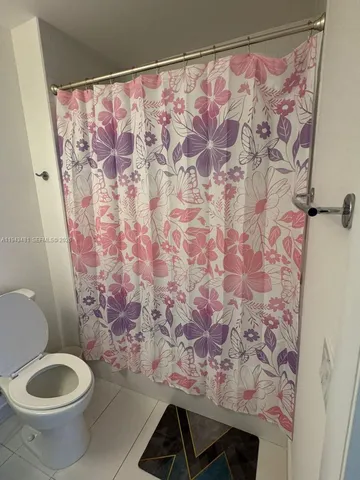 a bathroom with a toilet and a shower curtain