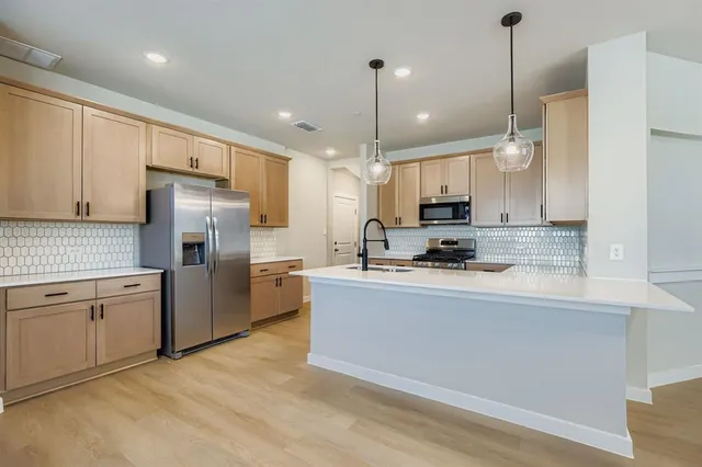 a kitchen with stainless steel appliances granite countertop a refrigerator a sink a stove and a oven