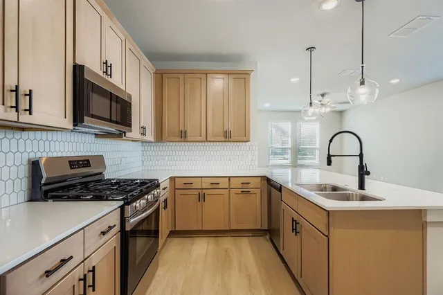 a kitchen with stainless steel appliances granite countertop a sink a stove and a microwave