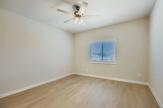 an empty room with a chandelier fan and windows