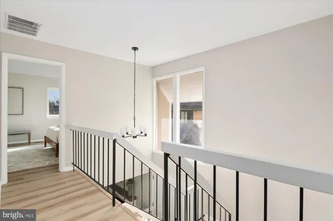 a view of a hallway with wooden floor and a bathroom