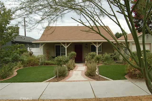 a front view of a house with a yard and potted plants
