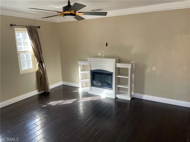 an empty room with wooden floor fireplace and windows