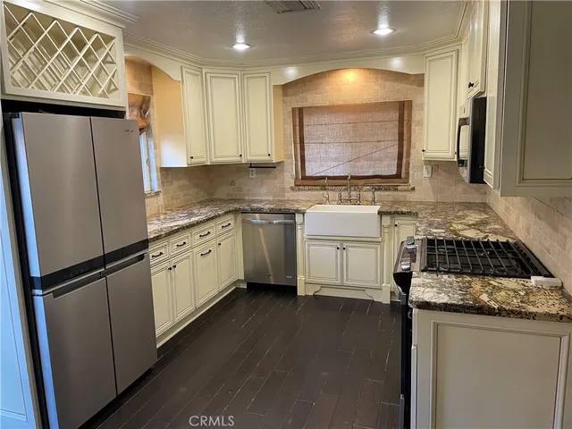 a kitchen with stainless steel appliances granite countertop a refrigerator a sink a stove a microwave and island with wooden floor