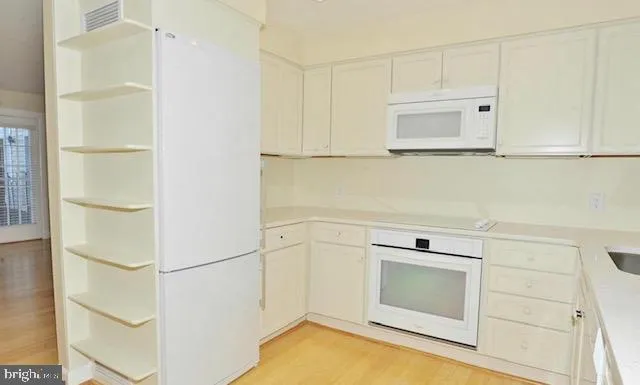 a kitchen with white cabinets and white appliances