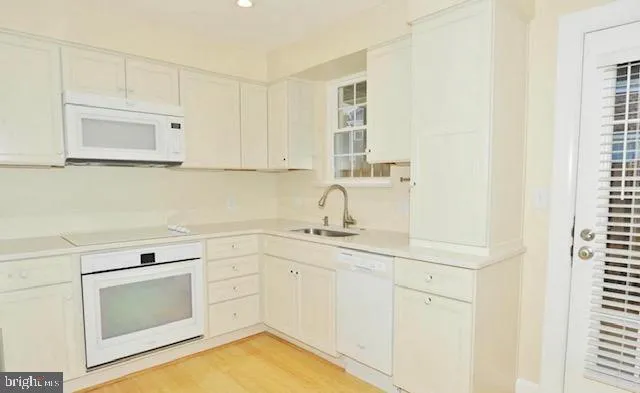 a view of a sink and dishwasher with wooden floor