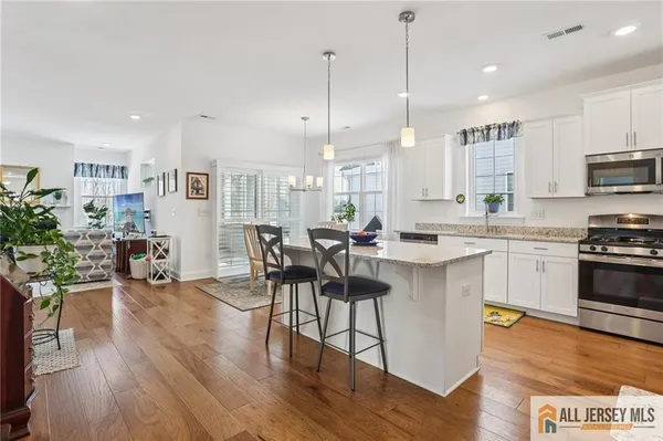 a kitchen with stainless steel appliances a dining table chairs stove and cabinets