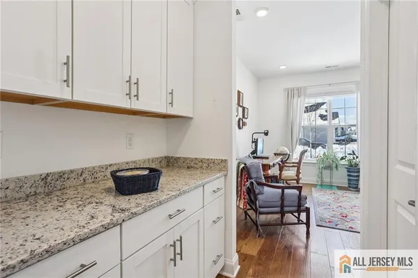 a kitchen with stainless steel appliances granite countertop a coffee maker on granite counter tops and white cabinets with wooden floor