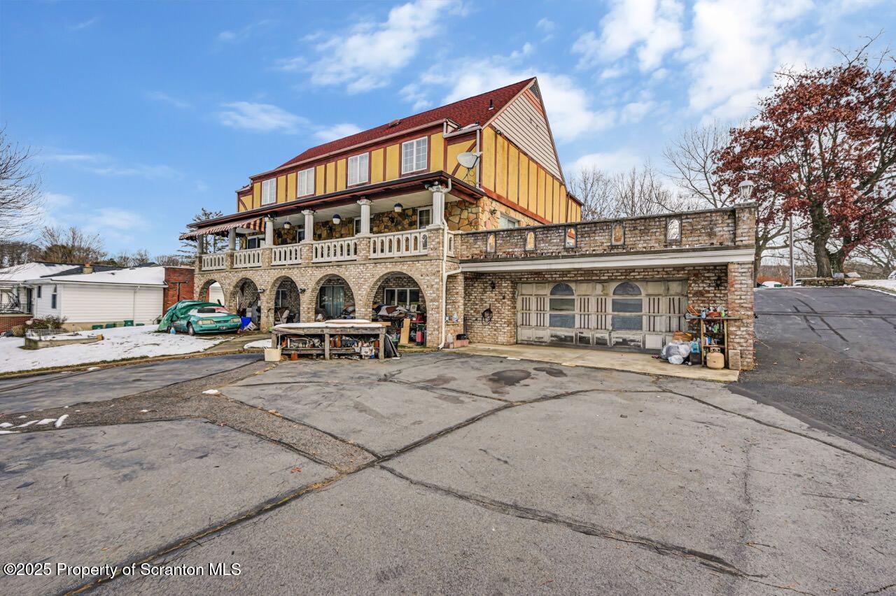 828 Glenwood Road Old Forge, PA 18518 - Photo 4 of 97 a view of a white house with large windows and a table and chairs under an umbrella