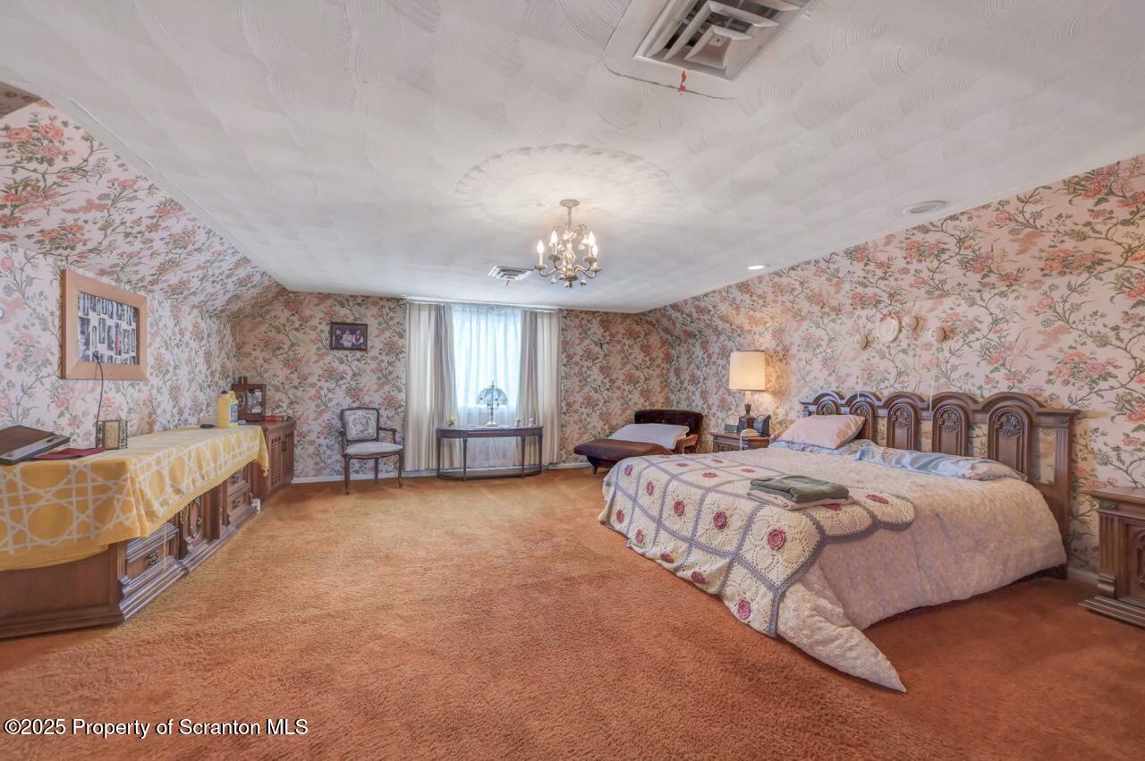 828 Glenwood Road Old Forge, PA 18518 - Photo 44 of 97 a spacious bedroom with two bed and a chandelier