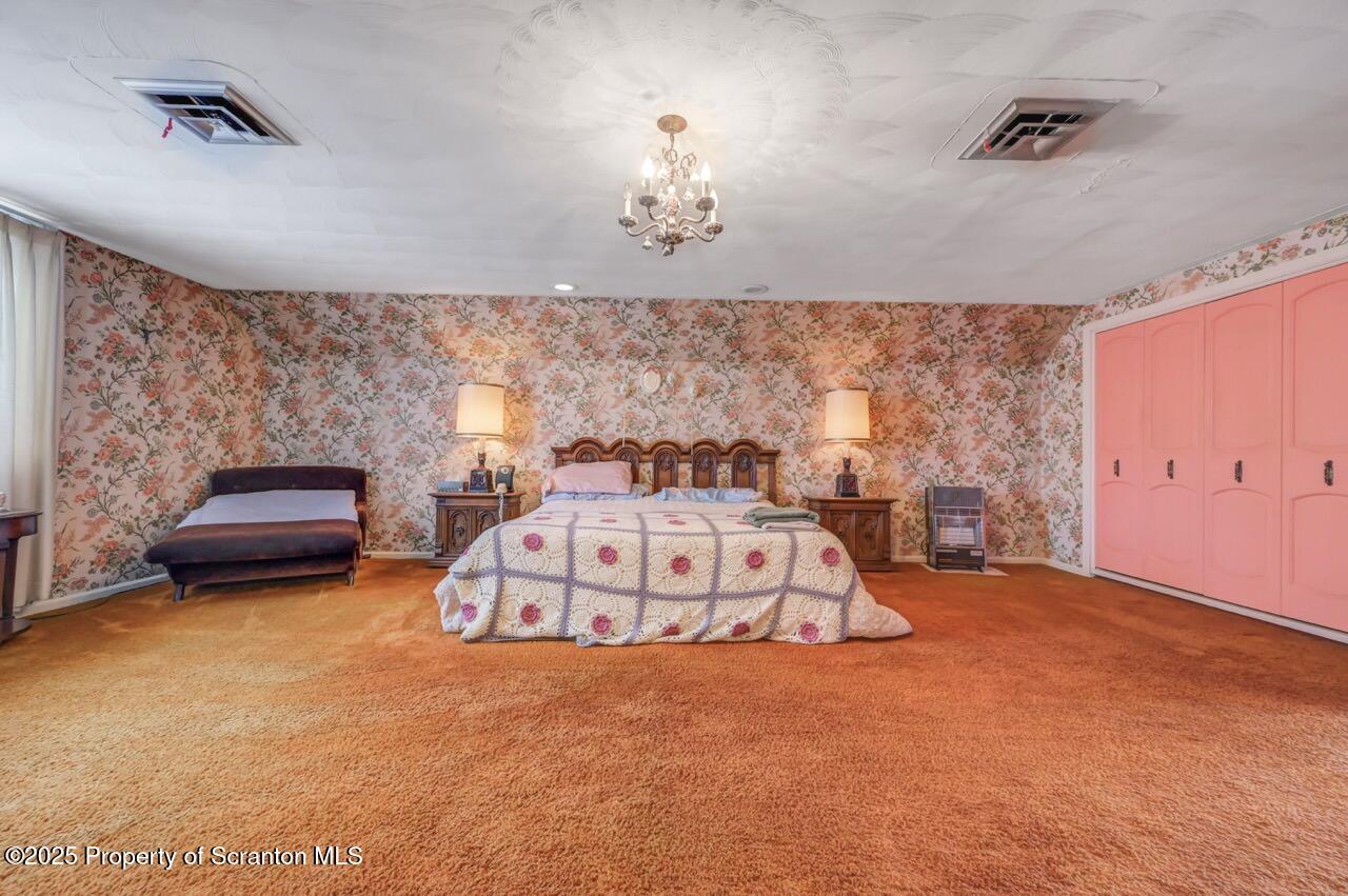 828 Glenwood Road Old Forge, PA 18518 - Photo 50 of 97 a spacious bedroom with a bed and a chandelier