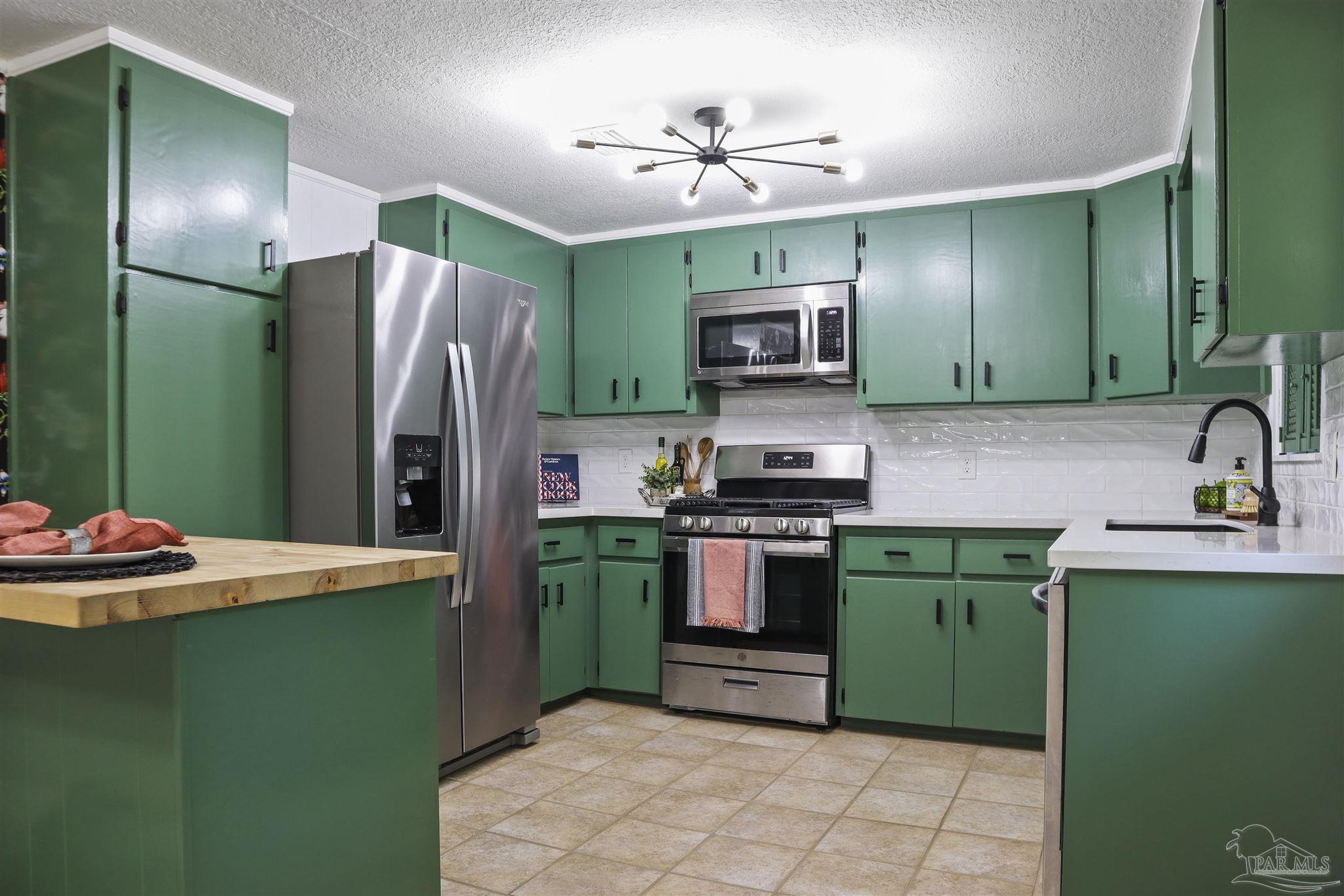 5925 Prince Road Pensacola, FL 32503 - Photo 9 of 51 a kitchen with kitchen island stainless steel appliances cabinets a sink and a refrigerator