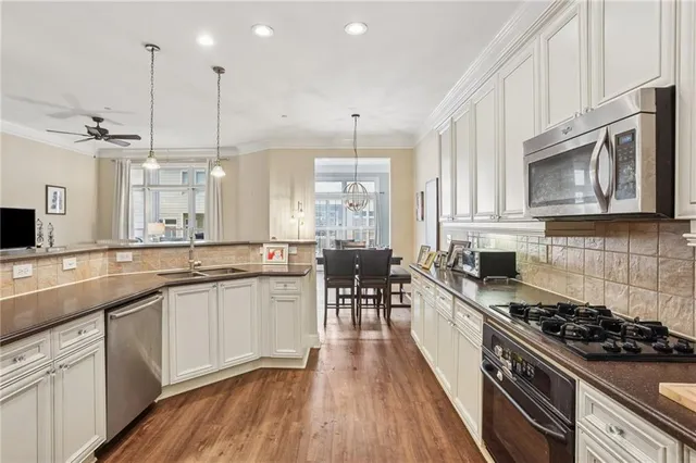 a kitchen with stainless steel appliances a stove a sink a microwave a center island and cabinets