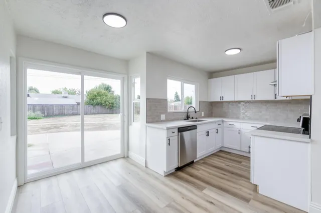 a kitchen with granite countertop a stove a sink and white cabinets with wooden floor