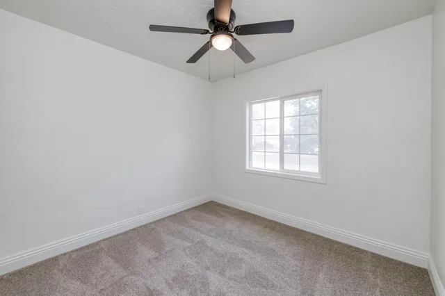 an empty room with a window and a fan
