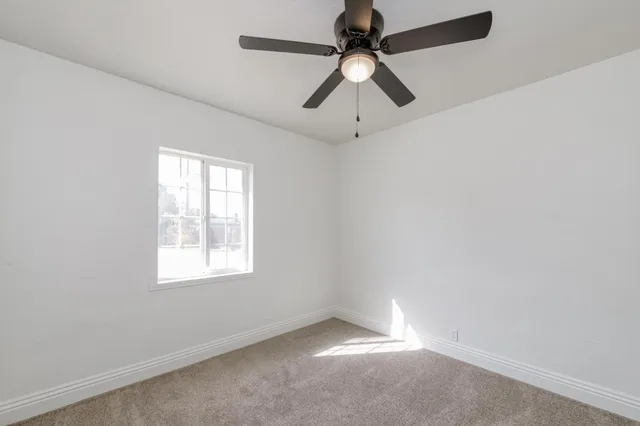 an empty room with a window and a fan