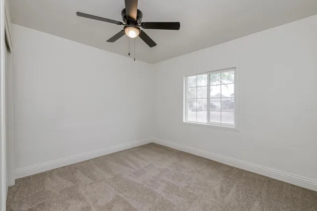 an empty room with a window and a fan