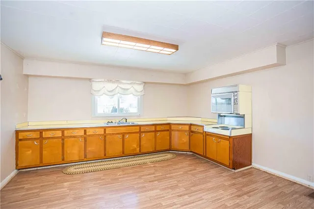 a large white kitchen with wooden floor and stainless steel appliances