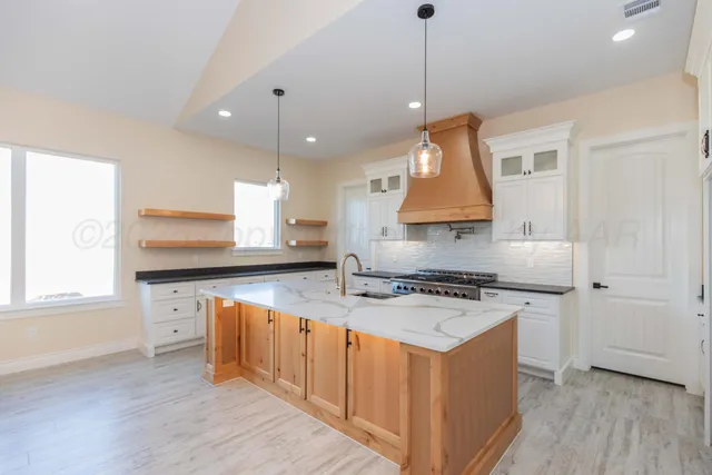 a kitchen with stainless steel appliances granite countertop a stove a sink and a wooden floor