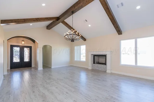 an empty room with wooden floor fireplace and windows