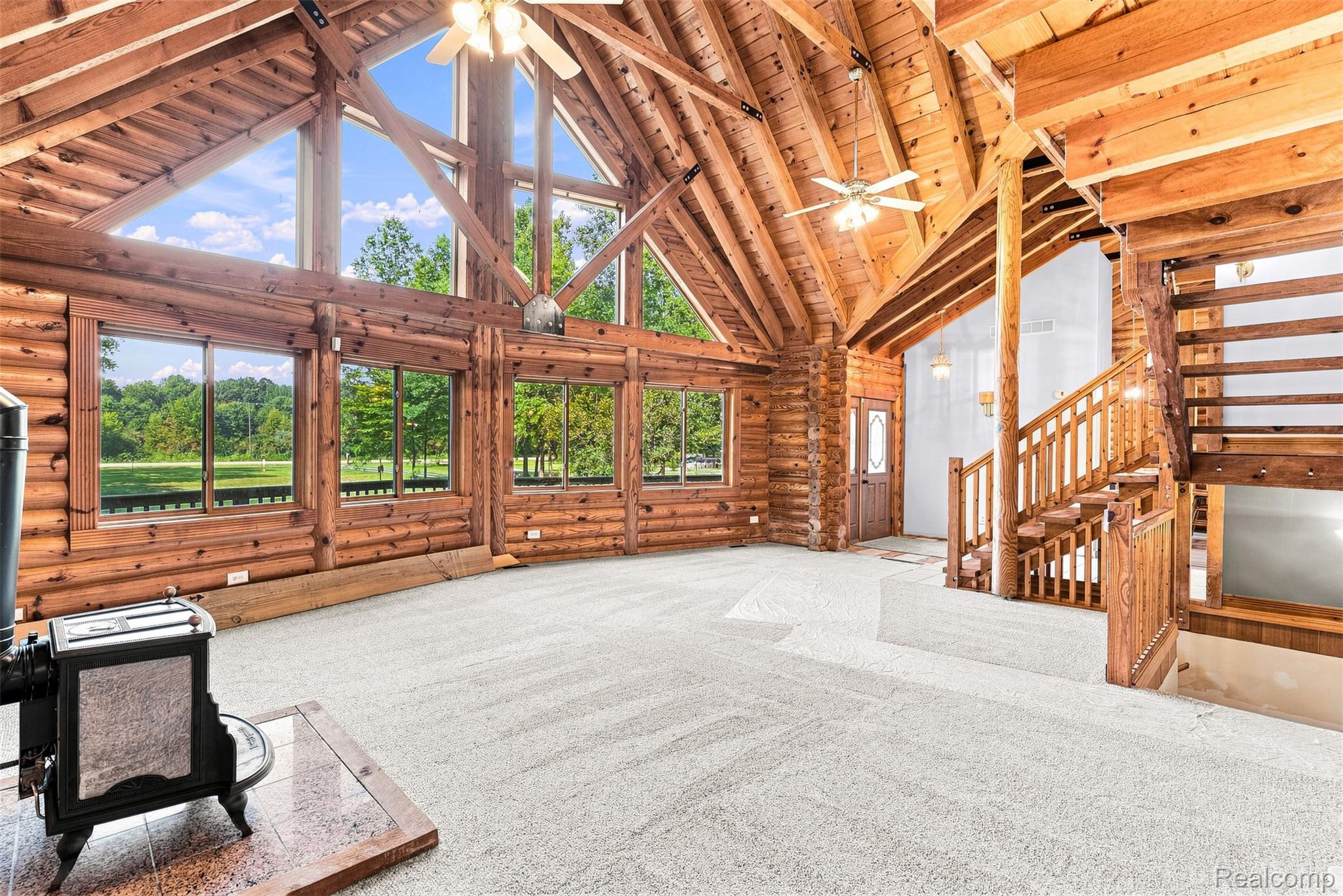 8340 North Nichols Road Flushing, MI 48433 - Photo 16 of 62 Vaulted wood-paneled ceiling, exposed beam construction, large picture windows, wood staircase with balusters, and a built-in wood-burning stove
